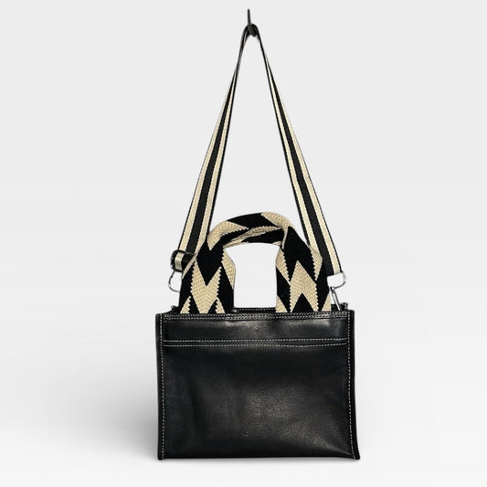 Black handbag with a patterned strap on a light gray background