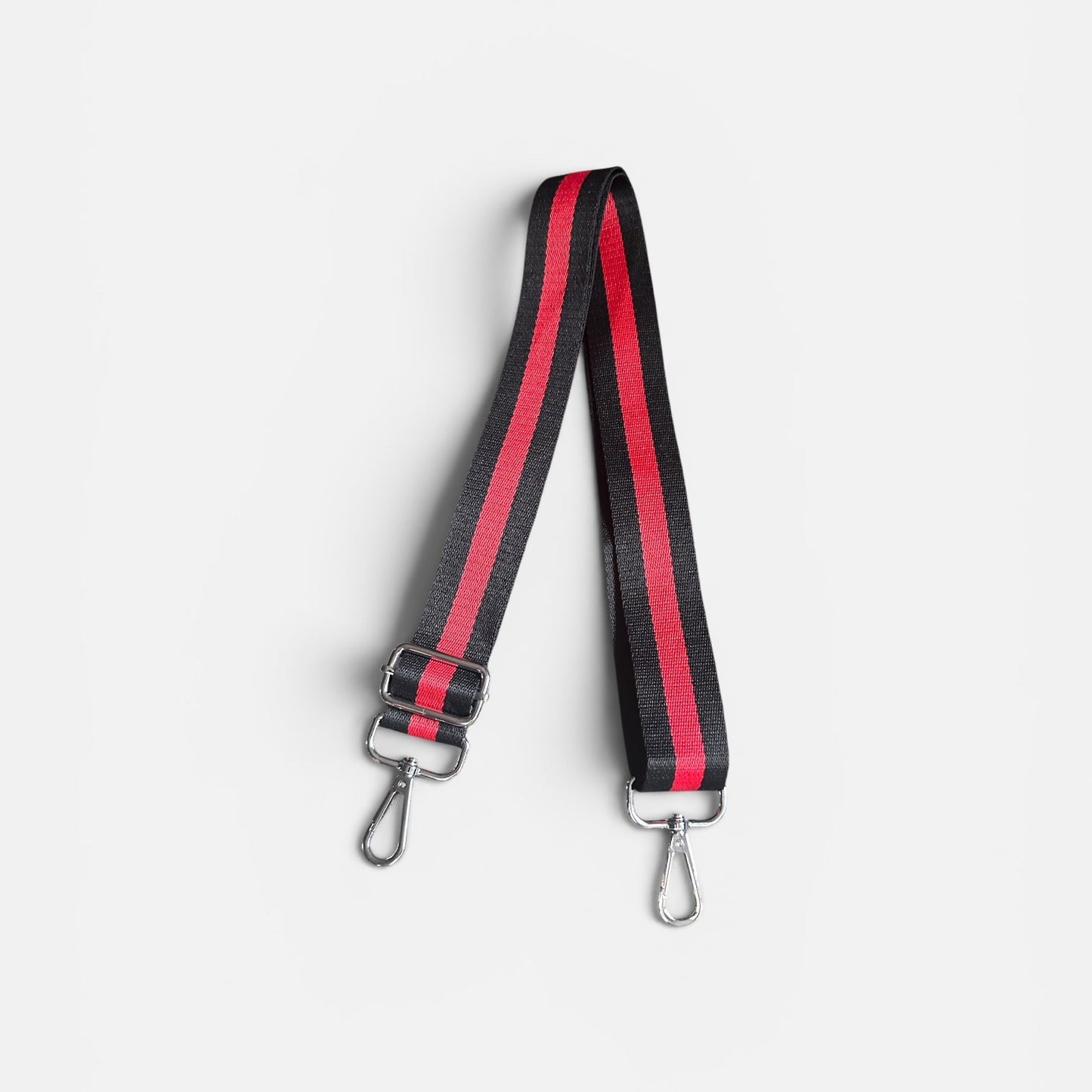 Black and red striped bag strap on a light gray background