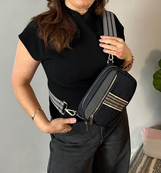 Black denim sling bag with colorful web.