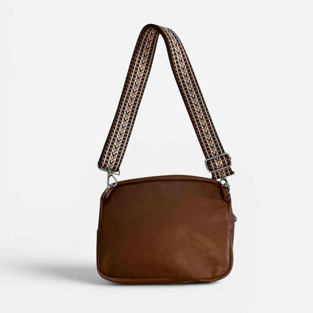 Brown leather bag with a woven strap on a light gray background