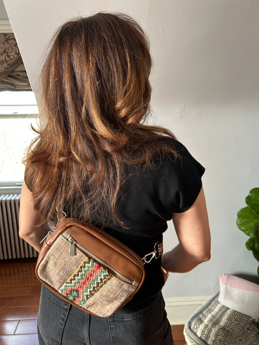 Leather and fabric sling bag with colorful web.