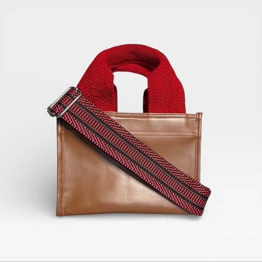 Brown leather bag with red knitted handle and strap on a light gray background