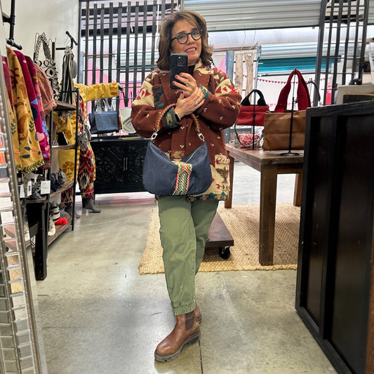 Woman taking a mirror selfie in a store holding a blue handbag.