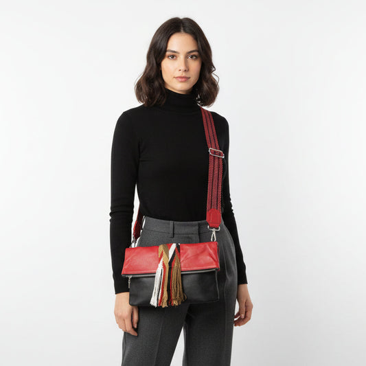 Red handbag with a scarf draped over a black mannequin in a white room.