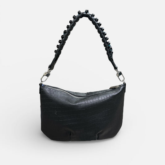 Black handbag with a textured handle on a light gray background
