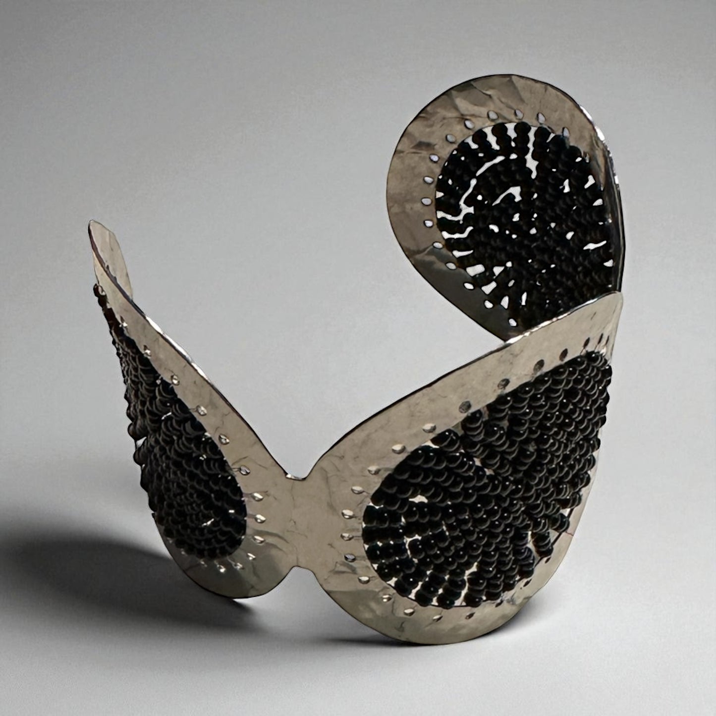 Metallic sculpture with a unique design on a gray background