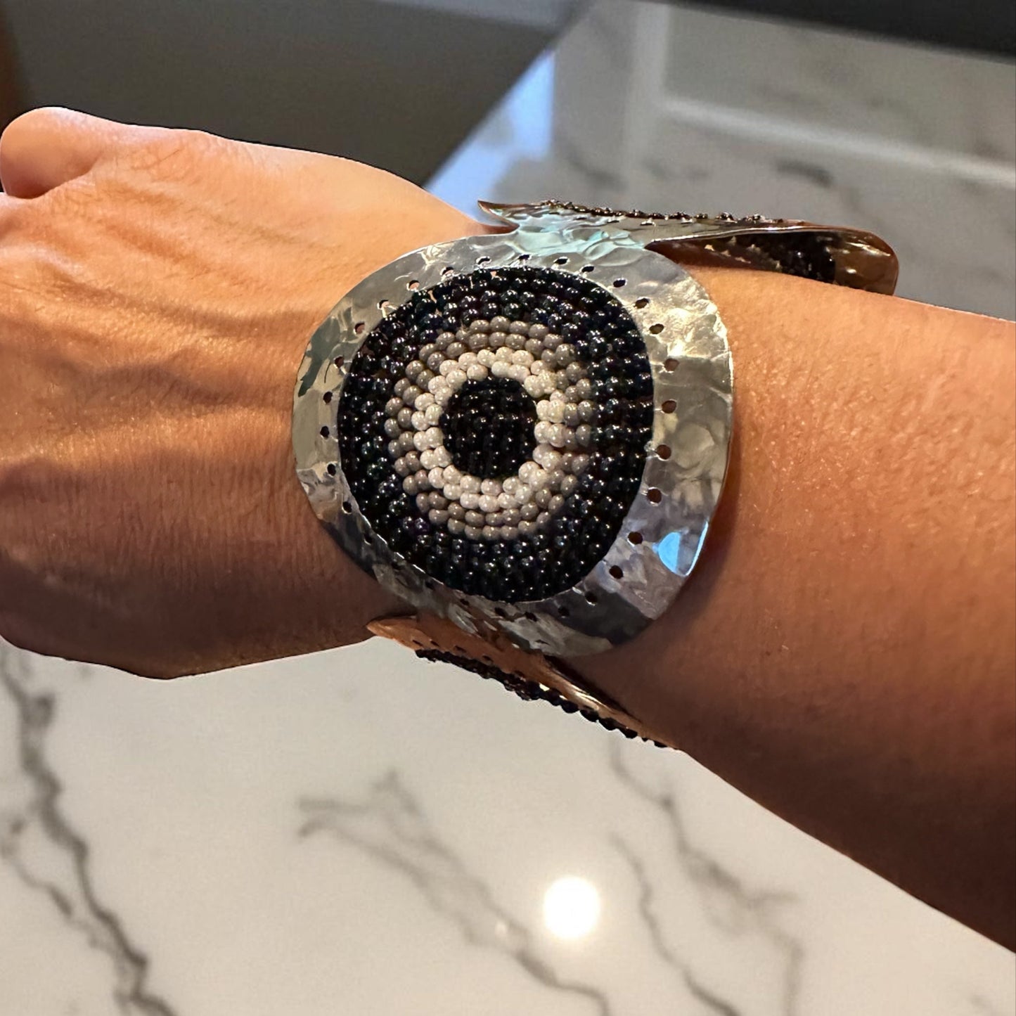 Close-up of a hand wearing a decorative bracelet on a marble surface