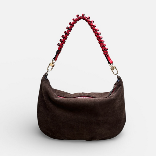 Brown handbag with a red beaded handle on a light gray background
