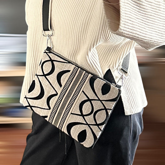 Person wearing a beige sweater and carrying a patterned bag with a blurred background