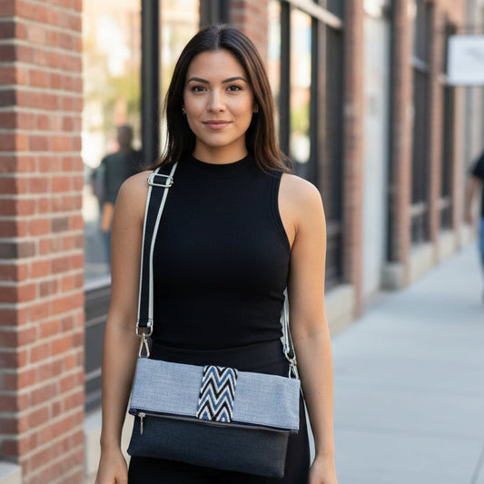 Gray and black handbag with a zigzag pattern on a mannequin against a brick wall.