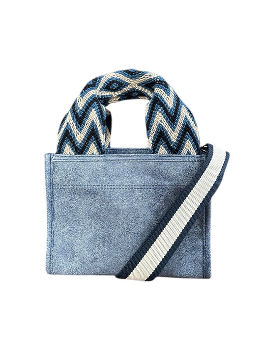 Blue denim handbag with a zigzag patterned handle on a white background