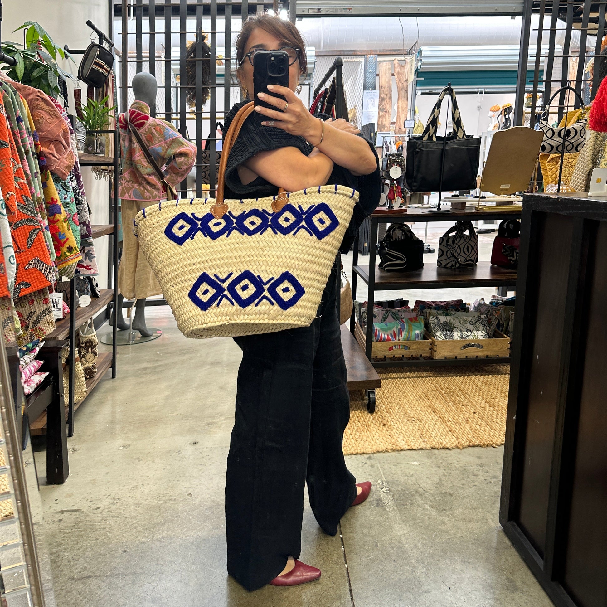 Person holding a woven bag with geometric patterns in an indoor setting.