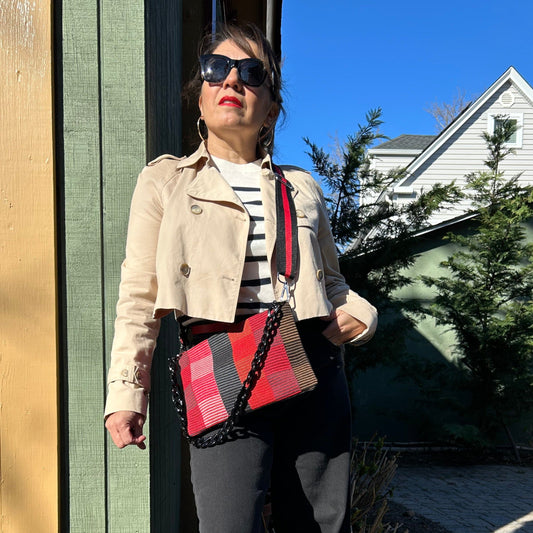 Person wearing a red and black plaid crossbody bag