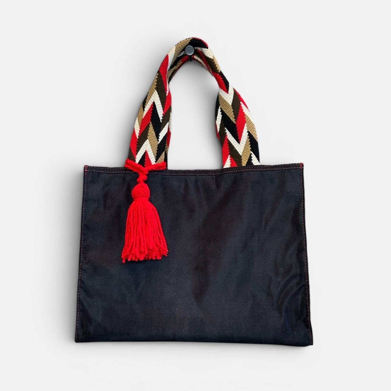 Black tote bag with colorful handle and red tassel on a white background