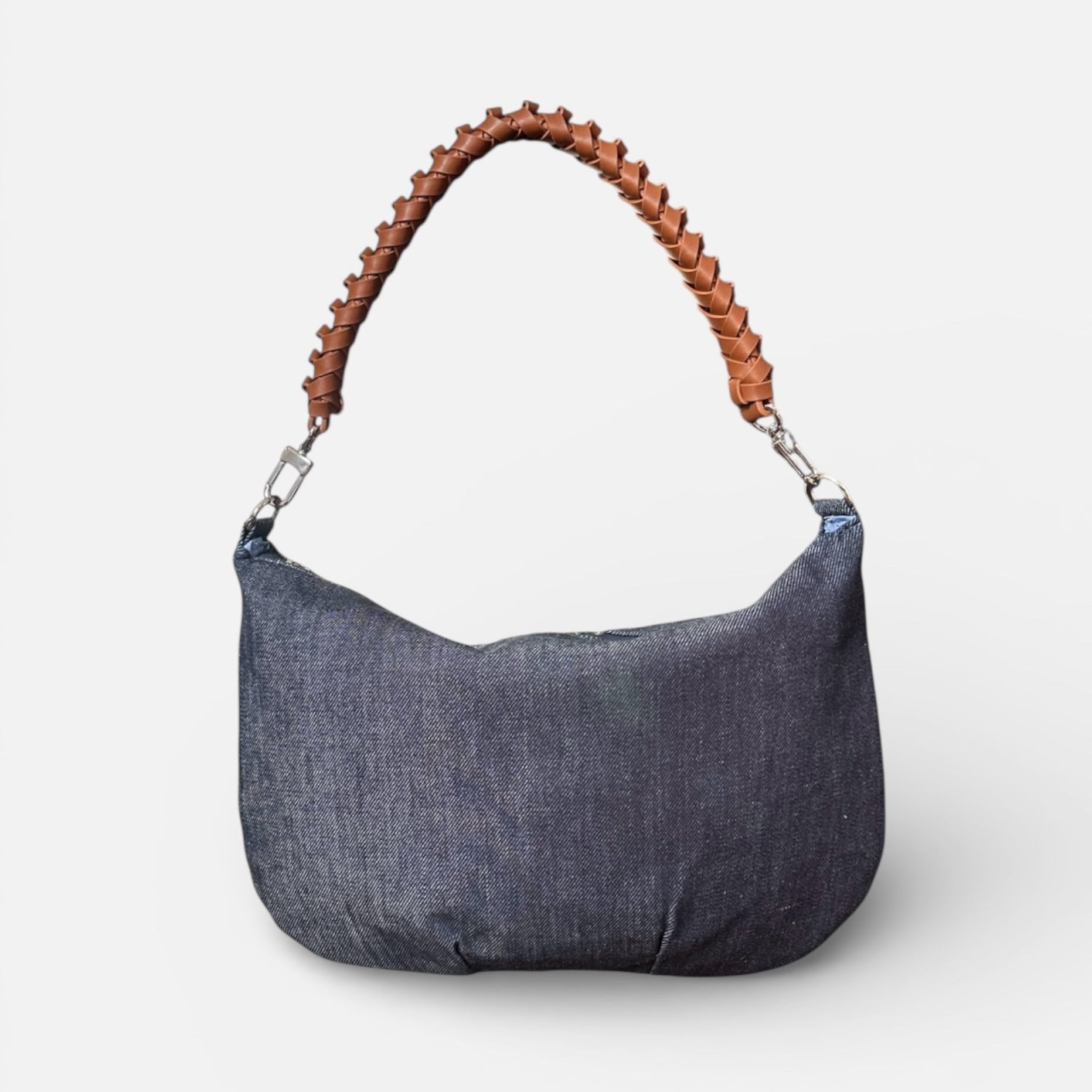 Blue denim handbag with brown leather handle on a white background