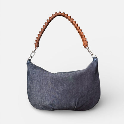 Blue denim handbag with brown leather handle on a white background