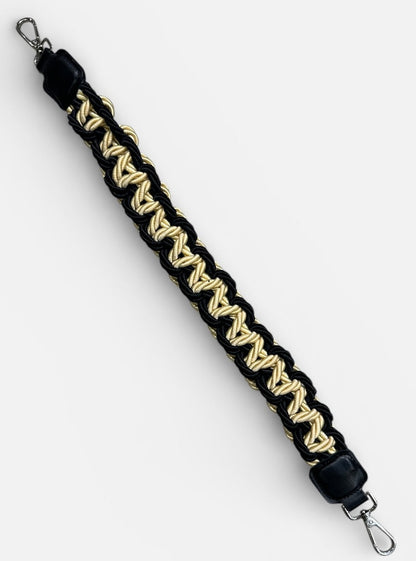 Black and gold braided strap with metal hooks on a white background