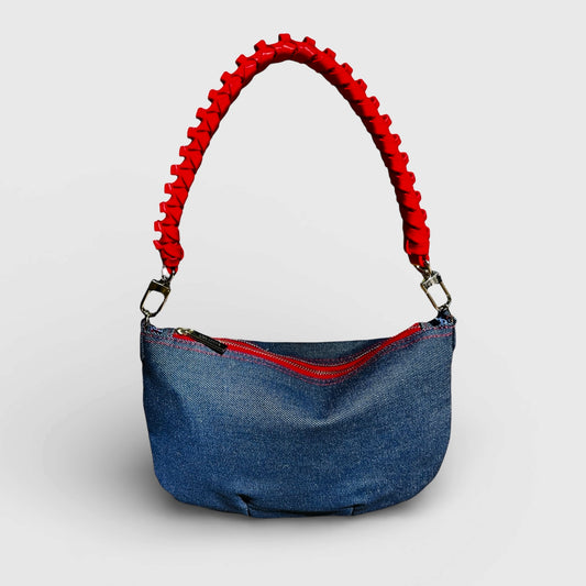 Blue handbag with red handle on a light gray background