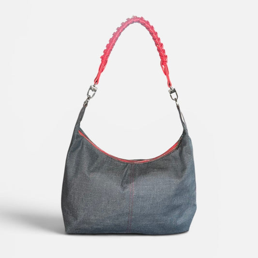 Medium blue denim slouchy shoulder bag featuring a red braided shoulder strap, relaxed silhouette, and spacious interior for everyday use.
