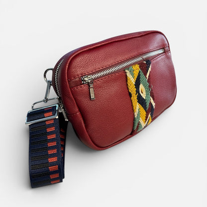 Red leather waist bag with colorful strap on a light gray background