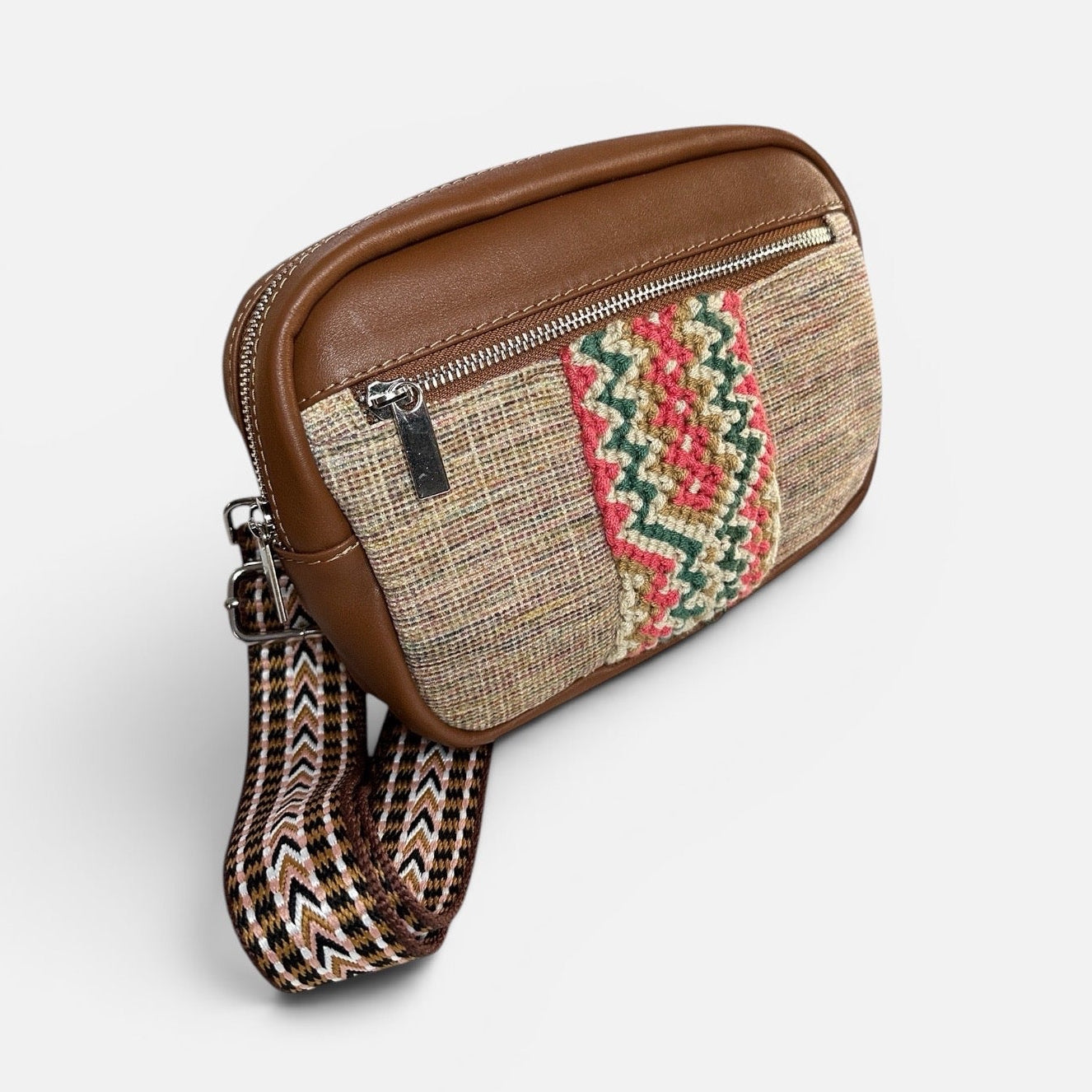 Brown leather and woven fabric crossbody bag on a light gray background