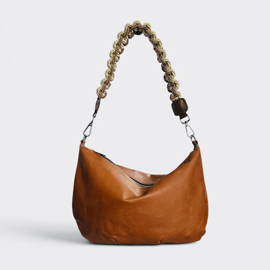light brown leather handbag with a braided handle on a light gray background