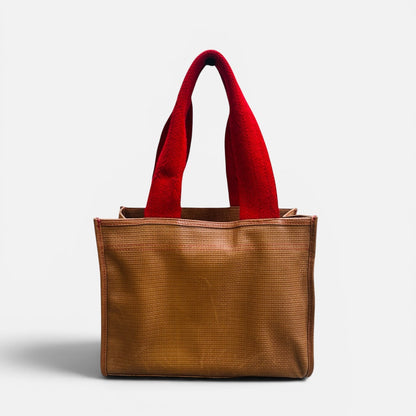 Brown tote bag with red handles on a light gray background