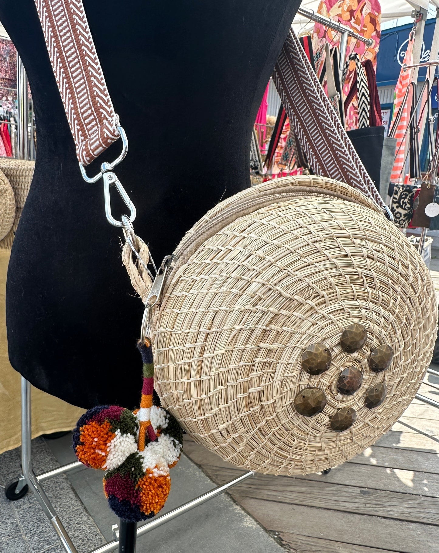 One of a kind straw crossbody bag with studs and pom poms.