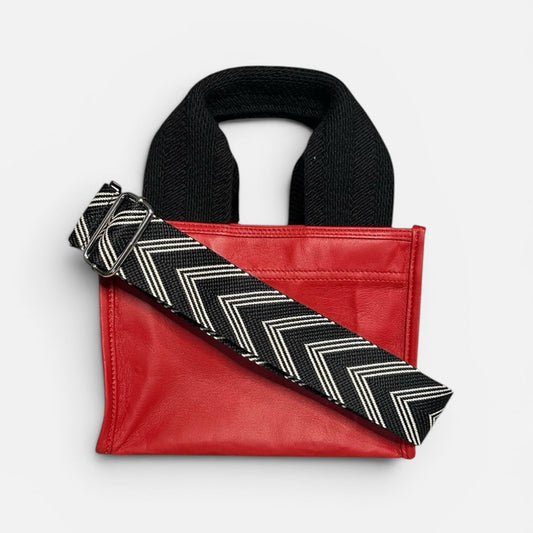 Red bag with a black and white zigzag strap on a light gray background
