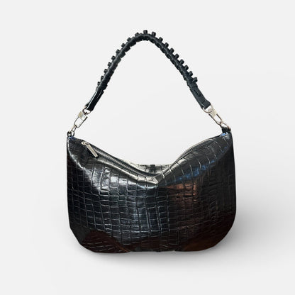 Black crocodile-patterned handbag with studded details on a white background