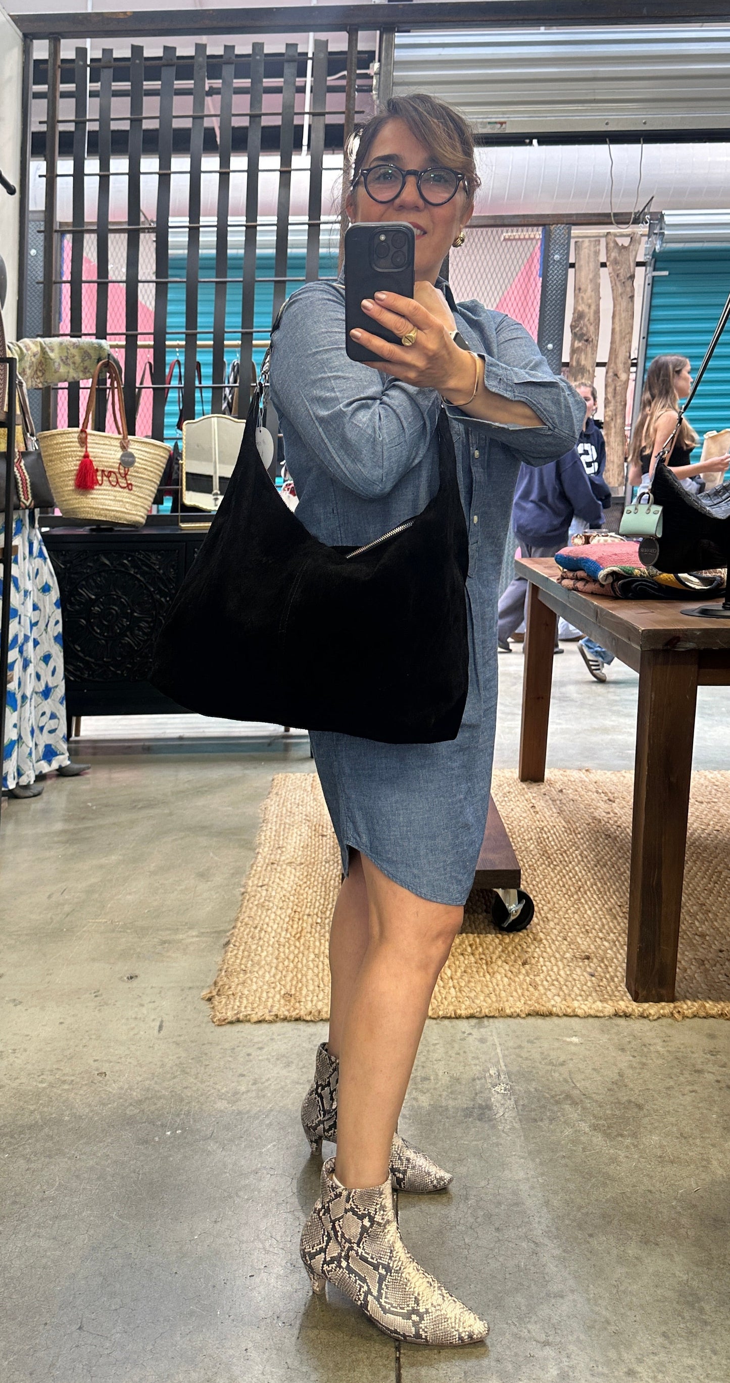 Large black suede slouchy shoulder bag featuring a handwoven Wayuu strap, spacious interior, and artisan craftsmanship for work, travel, and everyday style.