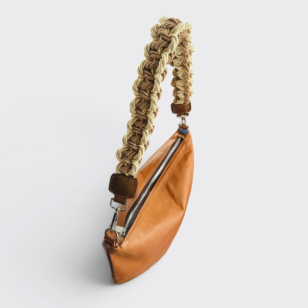 Brown leather pouch with braided handle on a light gray background