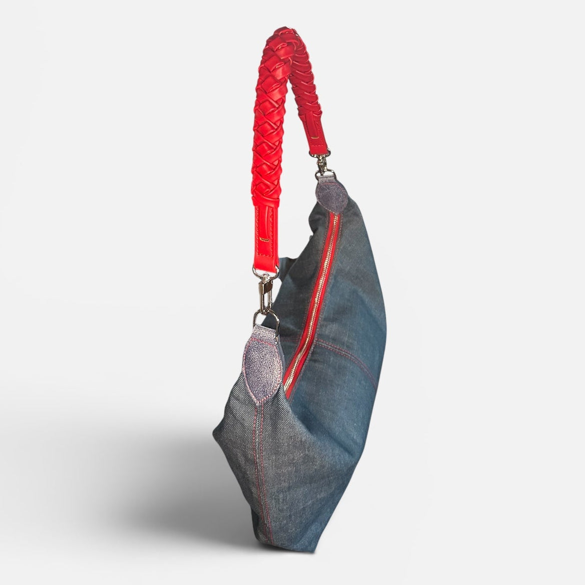 Medium blue denim slouchy shoulder bag featuring a red braided shoulder strap, relaxed silhouette, and spacious interior for everyday style.