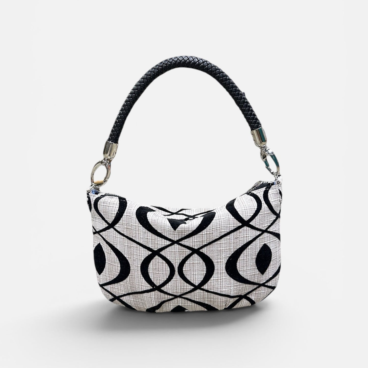 Black and cream patterned handbag on a light gray background 