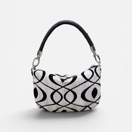Black and cream patterned handbag on a light gray background 