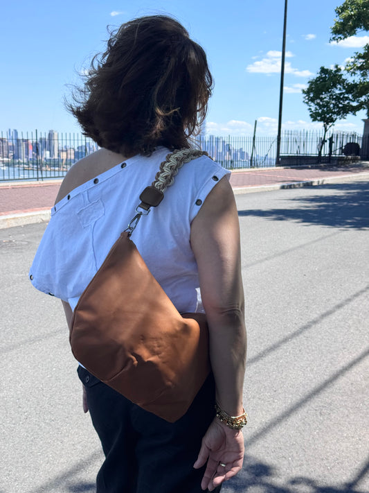 Caramel leather hobo shoulder bag featuring a handwoven cord shoulder strap, soft slouchy silhouette, and spacious interior for everyday use.