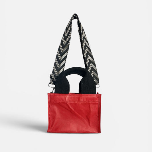 Red bag with a black and white zigzag strap on a light gray background