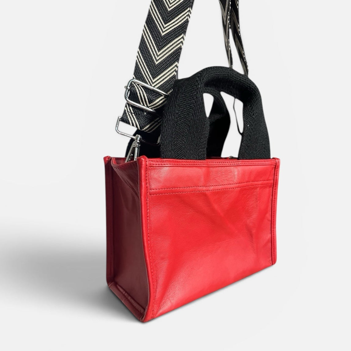 Red bag with a black strap and tie on a white background