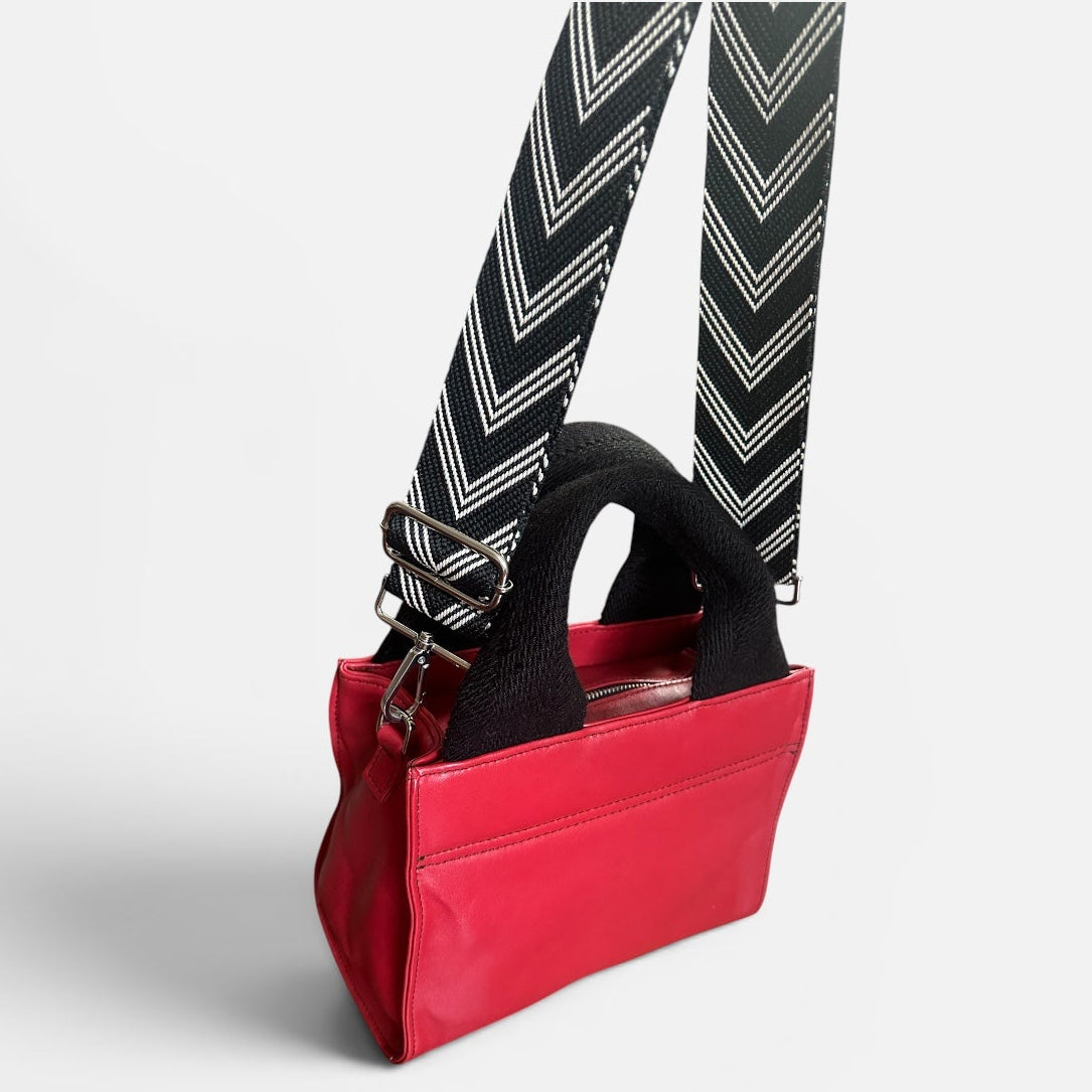Red handbag with a black strap on a white background