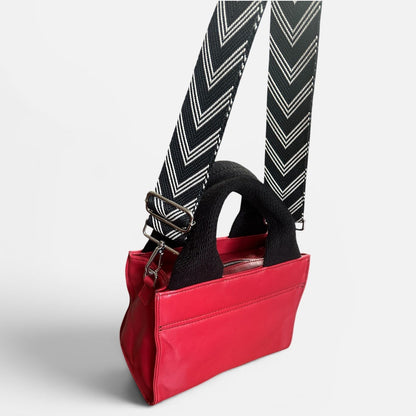 Red handbag with a black strap on a white background