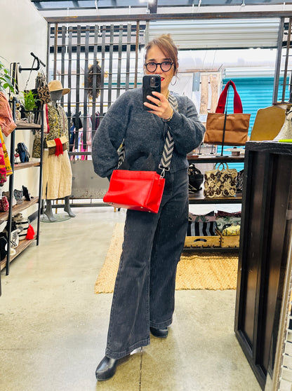 Person taking a mirror selfie in a store with a red handbag