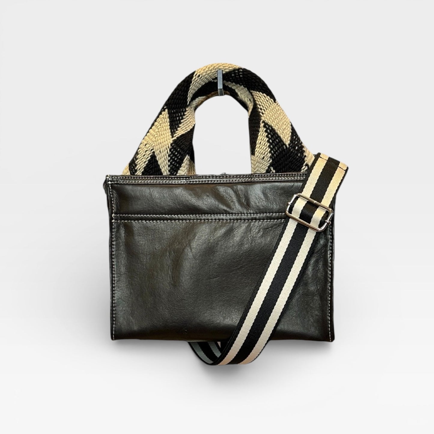 Black handbag with a striped strap on a light gray background
