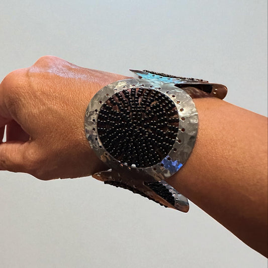 Hand wearing a futuristic metallic bracelet against a plain background