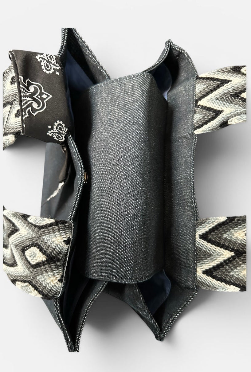 Black denim tote bag featuring vibrant multicolor handwoven Wayuu straps, combining durable denim with artisanal Colombian craftsmanship for everyday use.