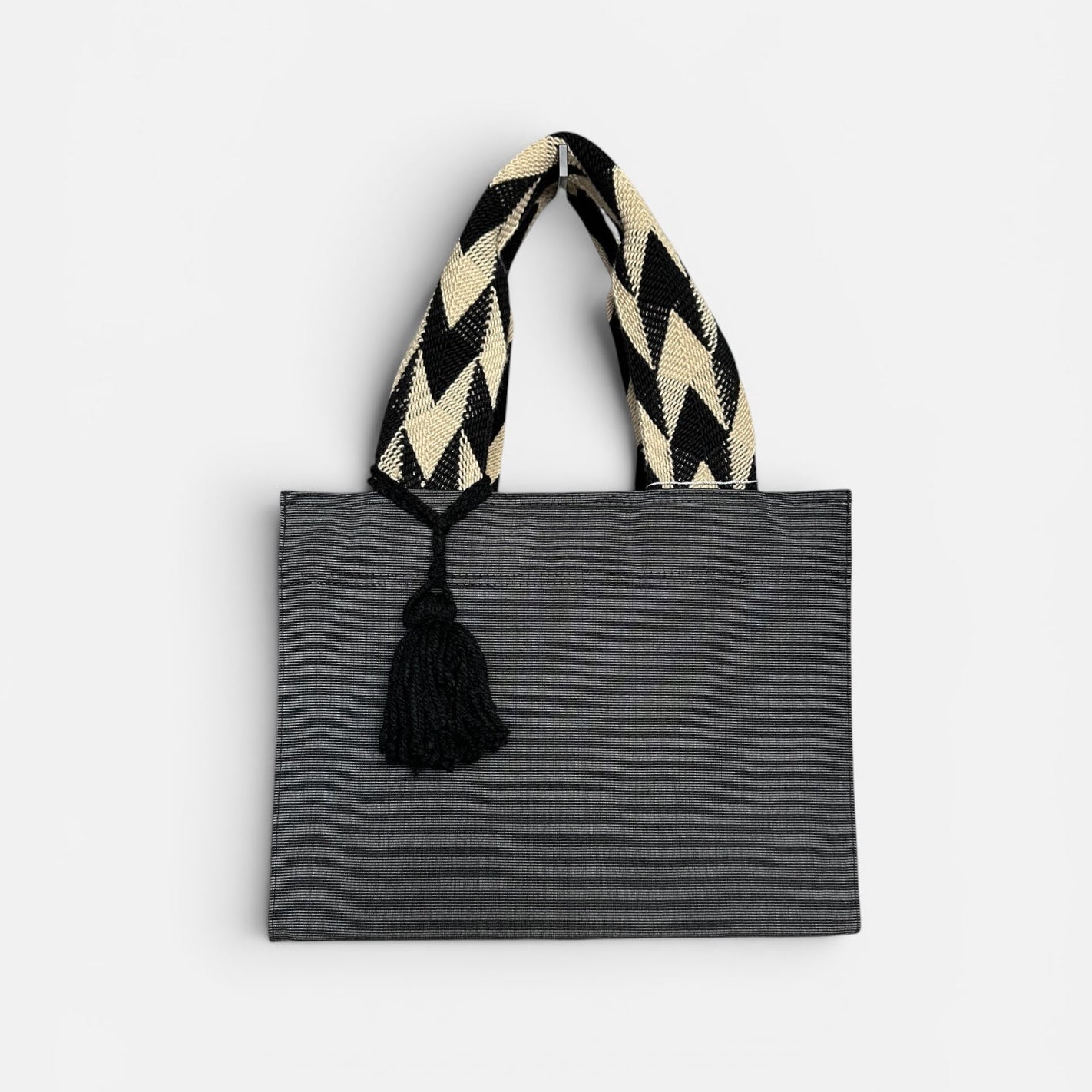 Gray tote bag with a black and white striped handle on a light gray background