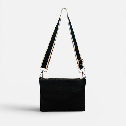 Black shoulder bag with a strap on a light gray background