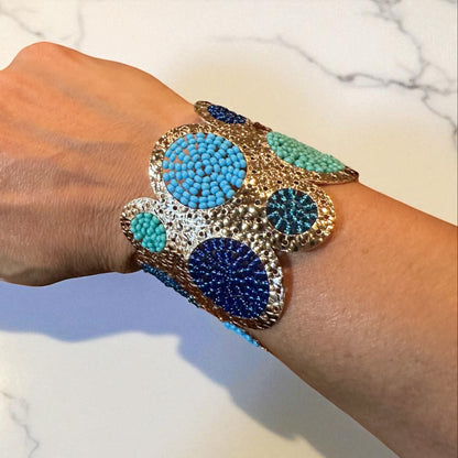 Hand wearing a colorful beaded bracelet on a marble surface