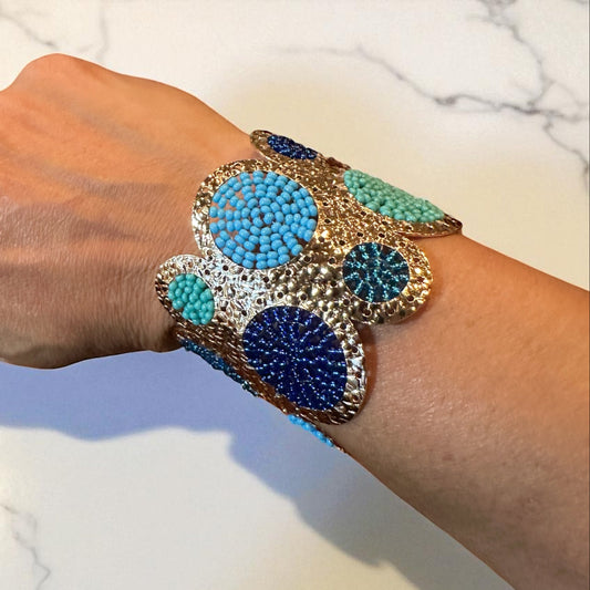 Hand wearing a colorful beaded bracelet on a marble surface