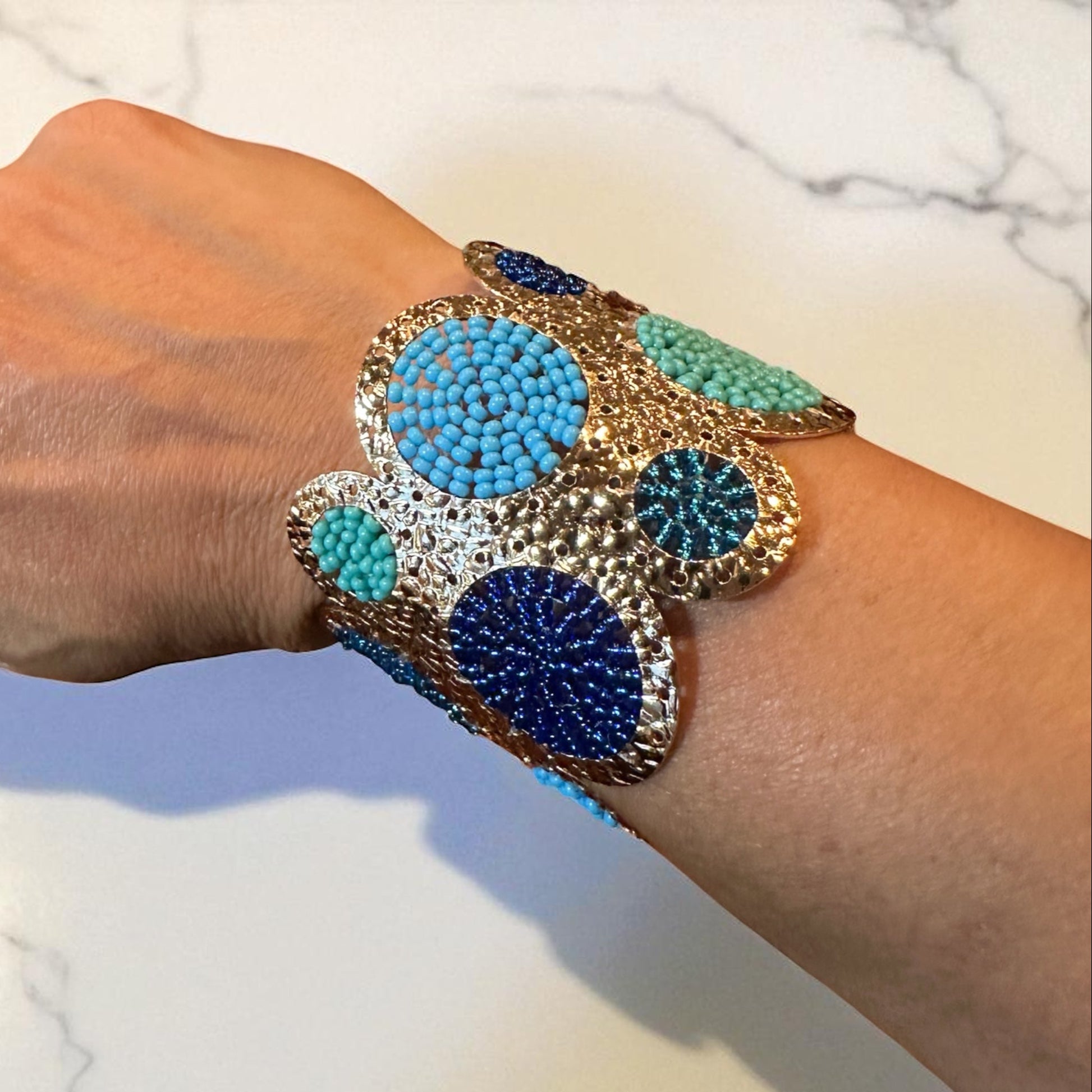 Hand wearing a colorful beaded bracelet on a marble surface