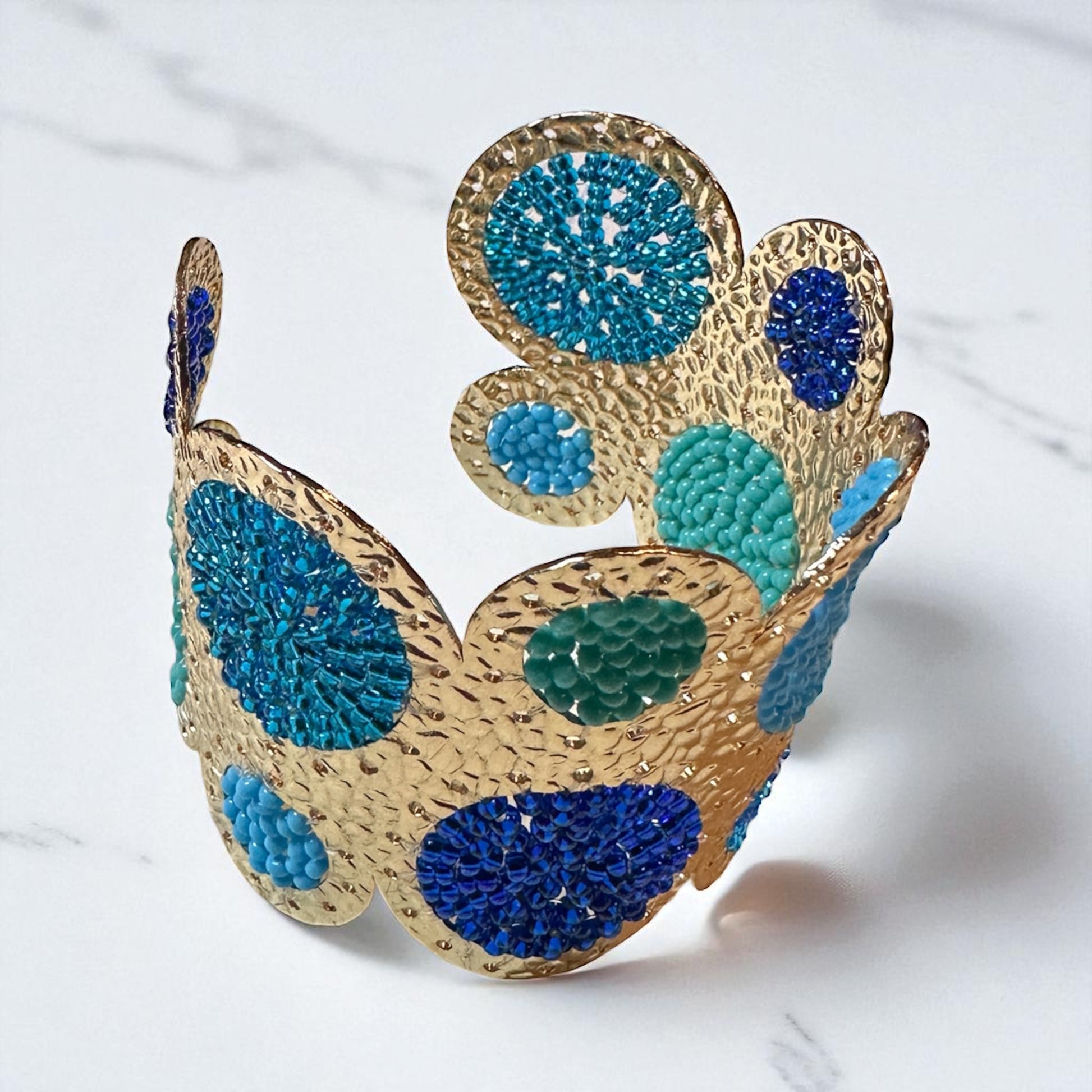 Gold and blue cuff bracelet on a white background